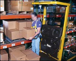 Order picker operator using full body harness.